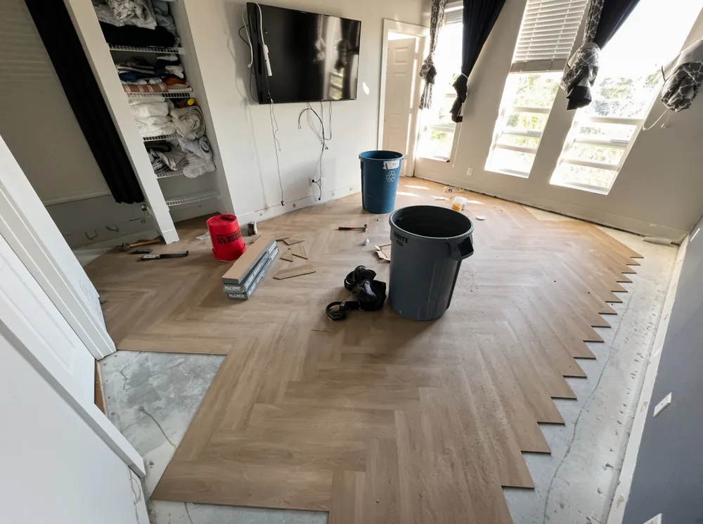 Herringbone luxury vinyl plank floor mid-installation in a bedroom